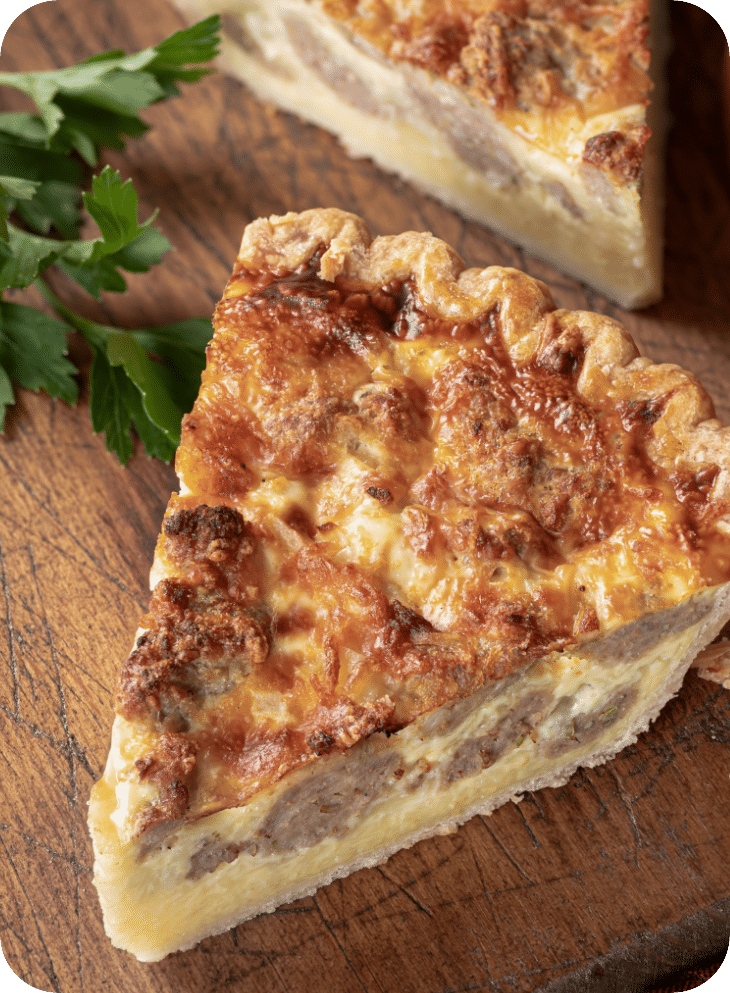 Una porción de quiche en una tabla de cortar de madera.